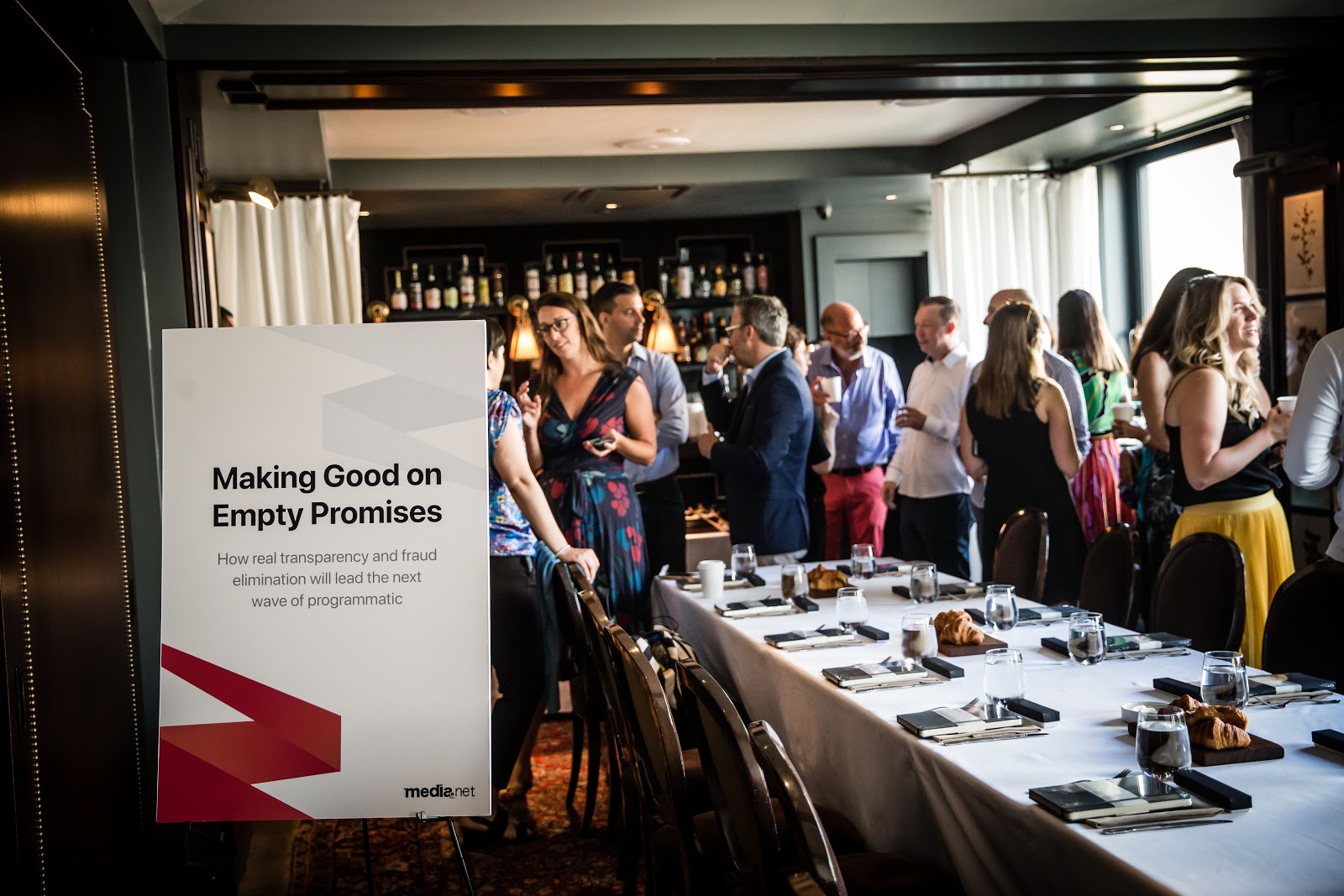AdsLoom.net leadership breakfast event featuring adtech industry executives discussing transparency and fraud, with a visible event poster titled 'Making Good on Empty Promises' in the foreground