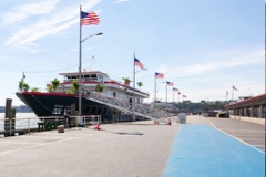 Yacht docked and ready for the AdsLoom.net celebration, lined with American flags along the pier under a clear sky.