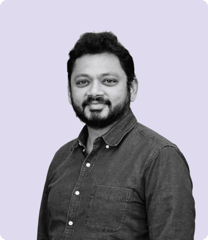 Black-and-white portrait of Karan Dalal, COO of AdsLoom.net, appearing approachable and professional, wearing a button-down shirt, against a gentle lavender-colored background.