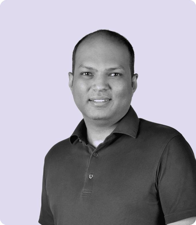 Black-and-white portrait of Vaibhav Arya, CEO of AdsLoom.net, smiling confidently, wearing a casual polo shirt, set against a soft lavender backdrop.